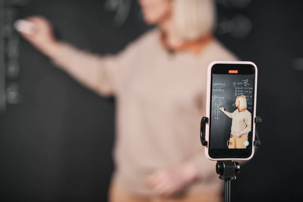 Teacher recording lesson on smartphone in class