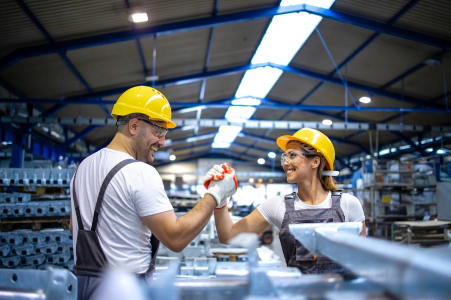 Factory workers handshaking each other at production line.